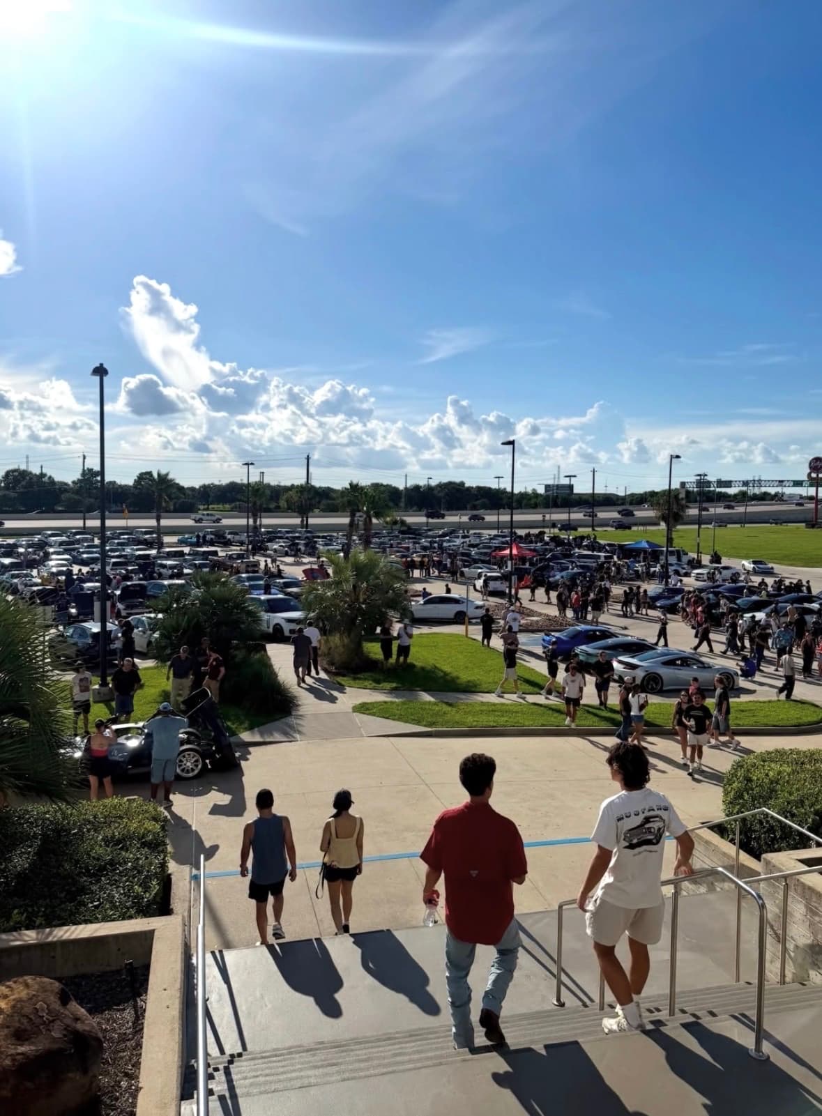 Attendees walking down the stairs toward the BL4NK meet under a blue sky