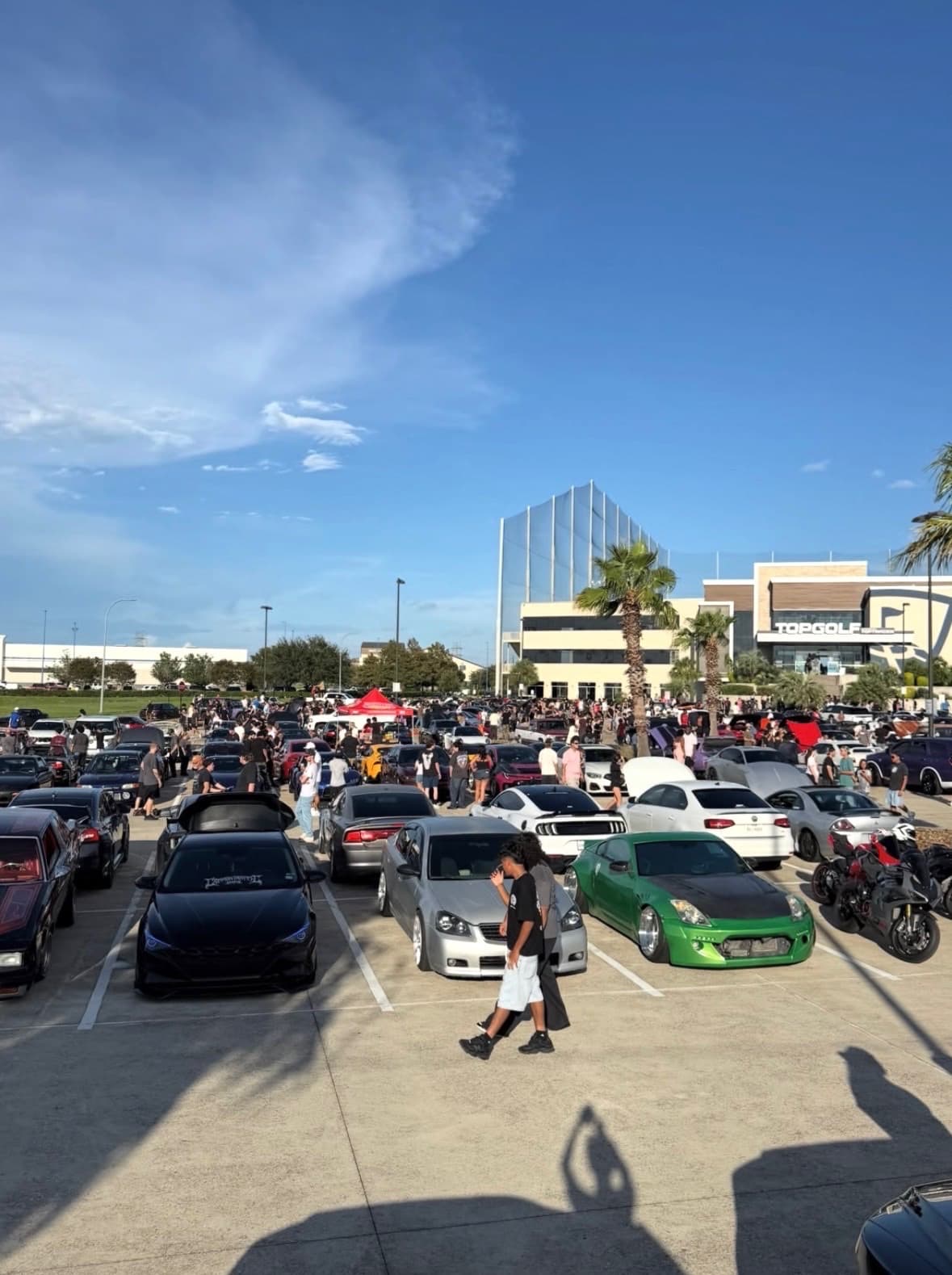 Wide view of the packed BL4NK meet parking lot with Topgolf in the background